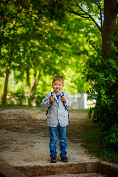 Cute little kid boy with backpack on green nature background. Back to school concept - Foto, Imagen