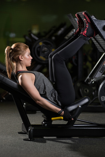 Sportive woman using weights press machine for legs. Gym. - Fotoğraf, Görsel
