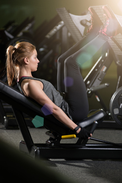 Sportive woman using weights press machine for legs. Gym. - Foto, Bild