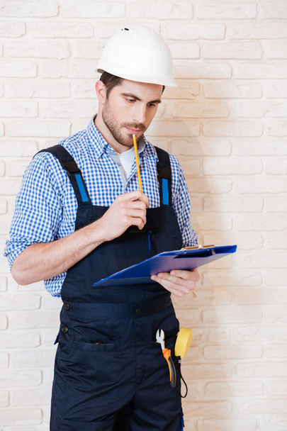 Construction worker thinking about something using clipboard - Photo, image