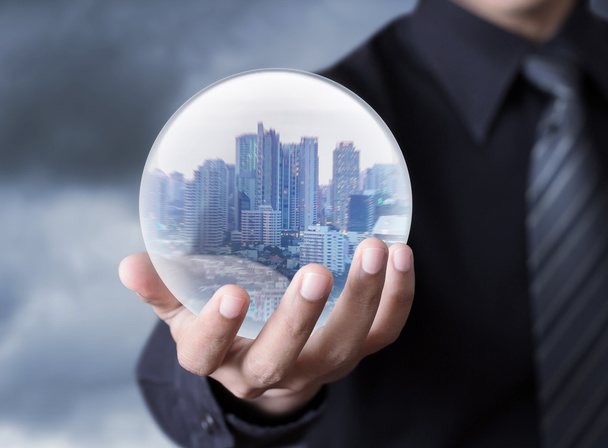 Hombre de negocios sosteniendo una ciudad dentro de una esfera
 - Foto, imagen