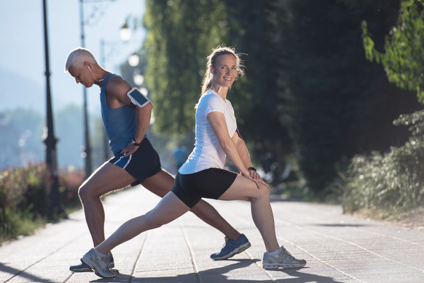 couple warming up and stretching before jogging - Foto, afbeelding