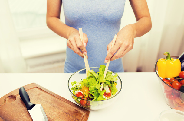 close up of woman cooking vegetable salad at home - Fotó, kép