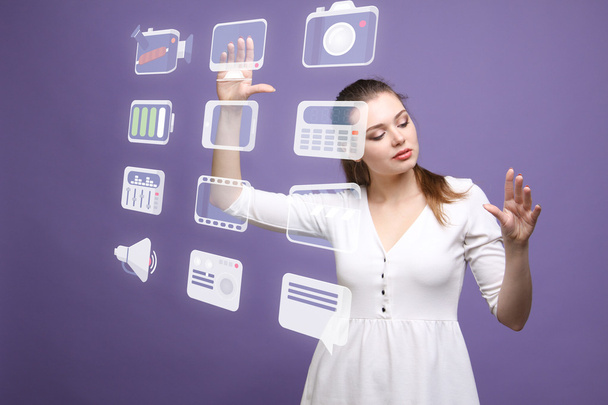 Woman pressing multimedia and entertainment icons on a virtual background - Photo, Image
