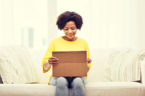 happy african young woman with parcel box at home - 写真・画像