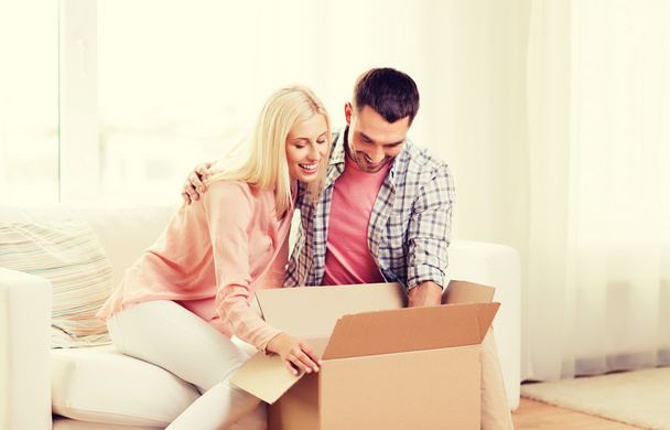 happy couple with cardboard box or parcel at home - Фото, изображение