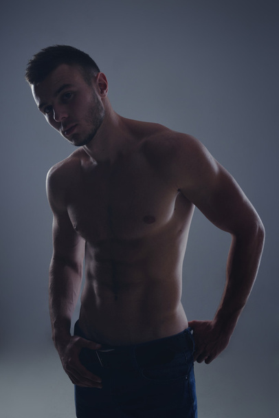 Young handsome guy posing in a studio with a beautiful body - Fotó, kép