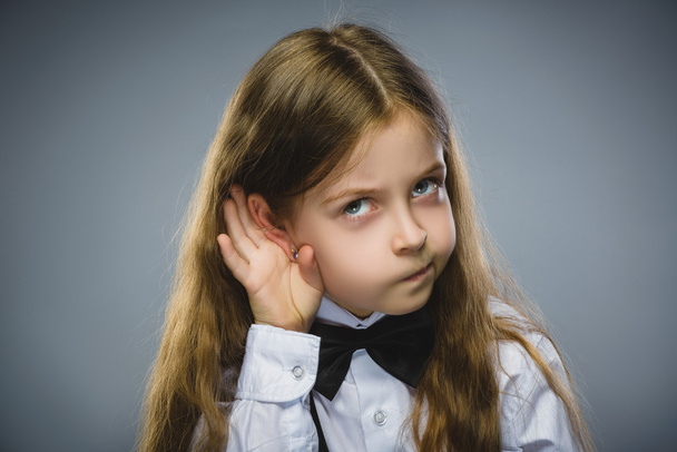 Curious Disappointed girl listens. Closeup portrait child hearing something, parents talk, hand to ear gesture isolated grey background. Human face expression, emotion, body language, life perception - Valokuva, kuva