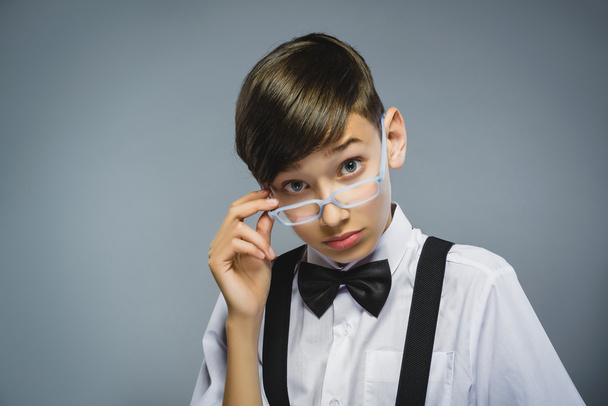 Closeup Thoughtful Young Boy with hand on glasses Against Gray Background - Fotó, kép