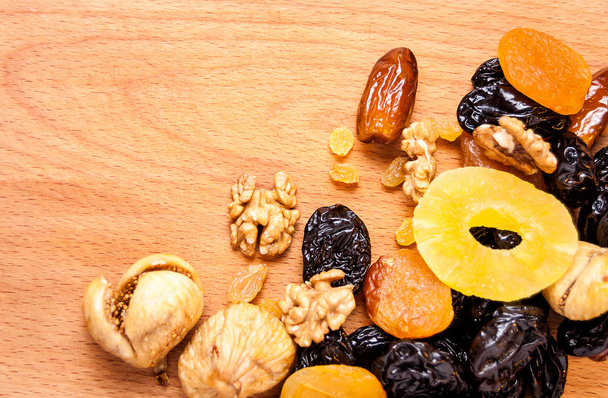 kandované pražené ořechy a sušené ovoce na dřevěné desce, organické potraviny - Fotografie, Obrázek