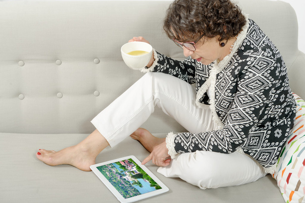 hermosa mujer madura con una tableta en el sofá
 - Foto, Imagen