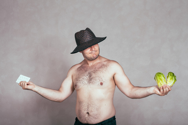 Uomo corpulento nudo indeciso con prodotti farmaceutici e vegetali
 - Foto, immagini
