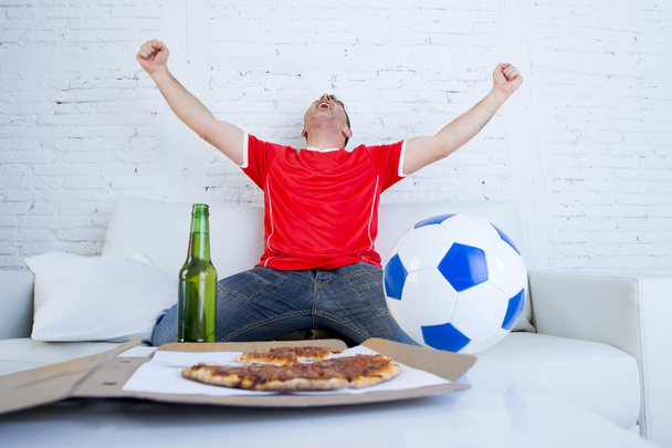 giovane tifoso di calcio uomo guardando partita in tv in maglia squadra celebrando gol pazzo felice sul divano
 - Foto, immagini