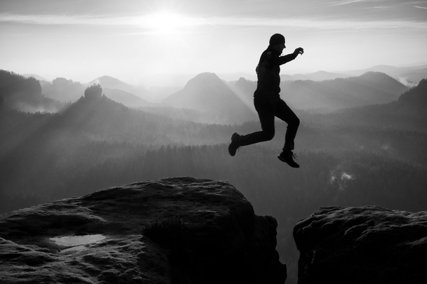 Crazyman  in black  jump between sharp rocks. - Photo, Image