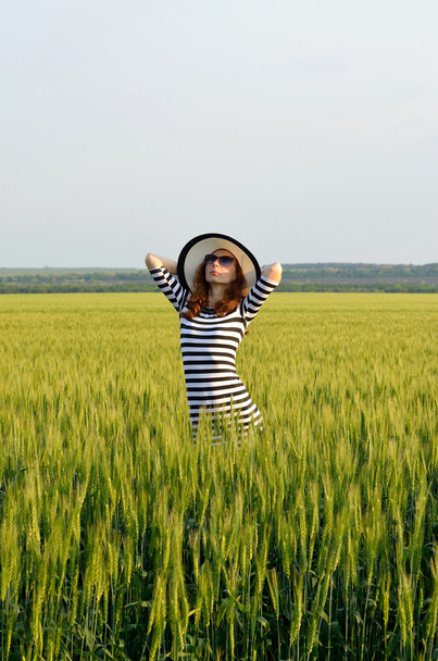 Młoda kobieta stwarzających w zdjęcie lato pole. - Zdjęcie, obraz
