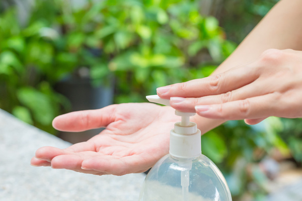 Female hands using wash hand sanitizer gel pump dispenser. - Photo, Image
