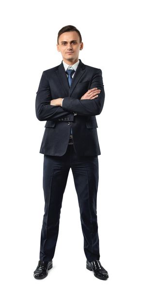Businessman in an elegant black suit stands with folded arms isolated on a white background. - Foto, Bild