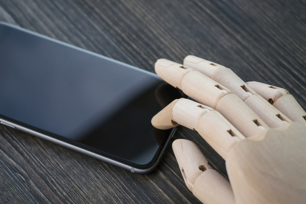 Искусственная деревянная рука с современным телефоном на доске
 - Фото, изображение