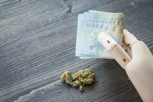 Mano artificial sosteniendo el dinero sobre las drogas
 - Foto, imagen