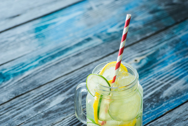 Jug with lemon and lime infused water on a rustic wooden surface - Photo, Image