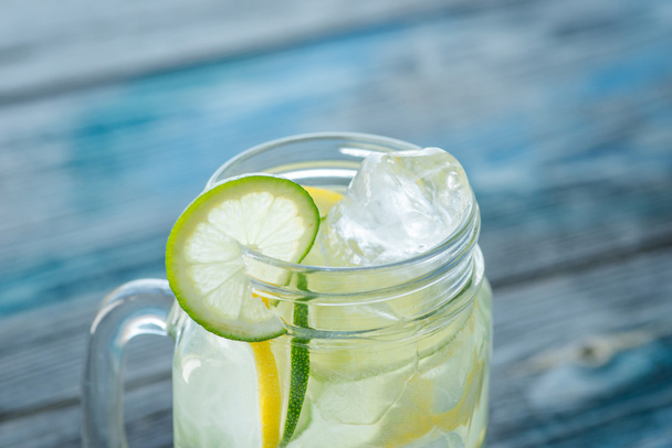Jug with lemon and lime infused water on a rustic wooden surface - Zdjęcie, obraz