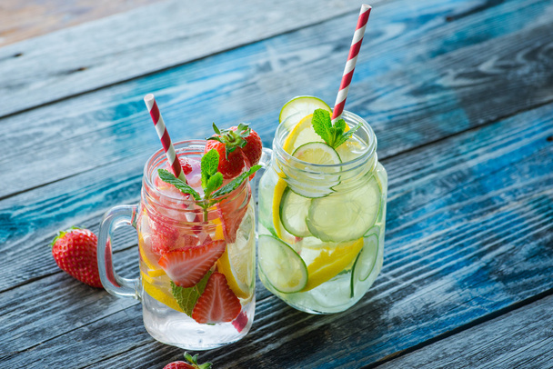 Jugs with lemon, lime and strawberry infused water on a rustic wooden surface - Foto, afbeelding