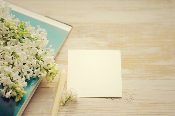 Bouquet of a white lilac on the open book and the white empty card for an inscription. - Foto, imagen