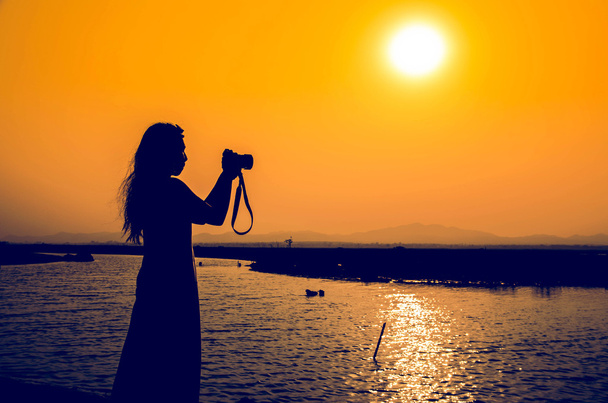 sillouette women photographer on lake at sunrise time - Photo, Image