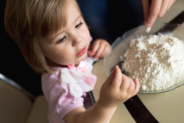 Little girl playiung with flour - Фото, изображение