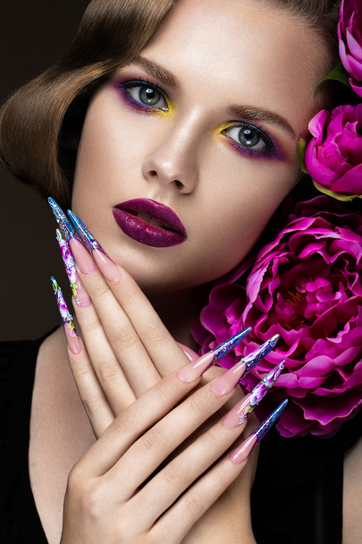 Beautiful girl with colorful make-up, flowers, retro hairstyle and long nails. Manicure design. The beauty of the face. - Photo, Image