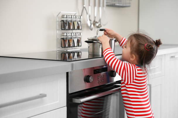 Little girl playing with electric stove in kitchen - 写真・画像