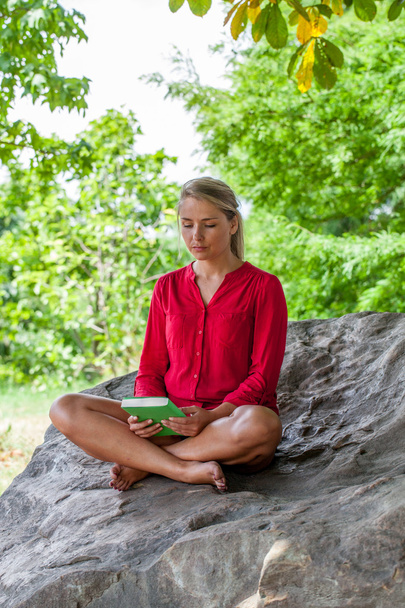 20 代の笑顔の木の下で夏の本を読んでいる女の子 - 写真・画像
