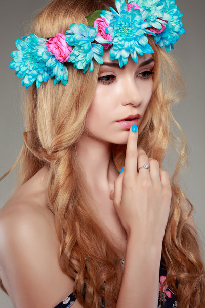 Hermosa chica, aislada sobre un fondo gris claro con flores varicolores en pelos, emociones, cosméticos
 - Foto, Imagen