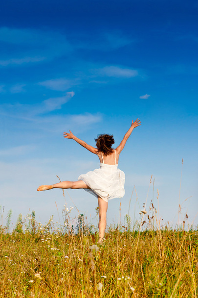 young woman jumping in the meadow - Foto, afbeelding