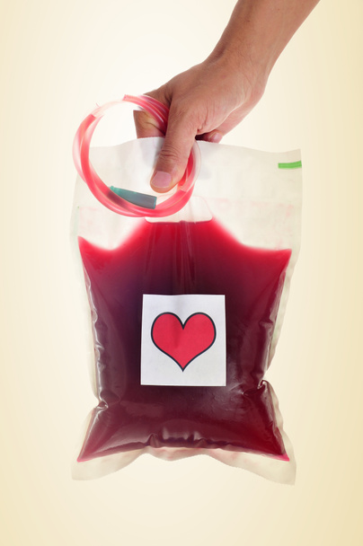 kan torbası ile bir etiket, bir kırmızı kalp tutan adam - Fotoğraf, Görsel