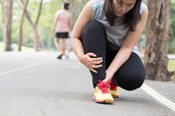 Lesiones deportivas. Mujer con dolor en el tobillo mientras trota
 - Foto, Imagen