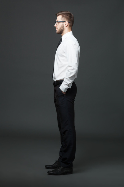 Fullbody profile view of handsome businessman on dark gray backg - Fotoğraf, Görsel
