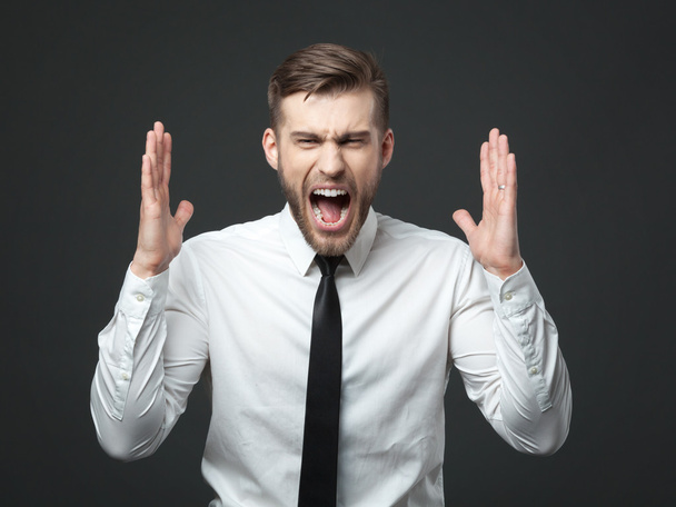 Young businessman screaming at camera isolated. - Фото, изображение