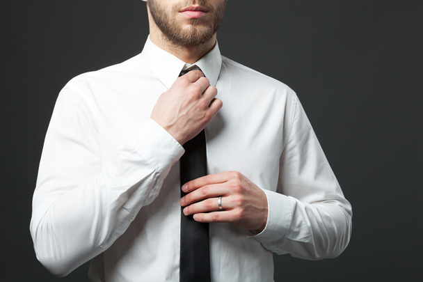 Mid section of young fit businessman adjusting tie isolated. - Foto, imagen