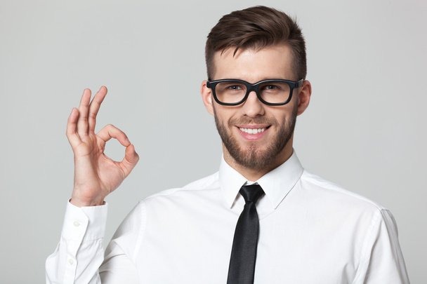 Handsome businessman showing okay sign on gray background. - Photo, image