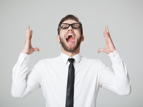 Young businessman screaming -  isolated on gray background. - 写真・画像