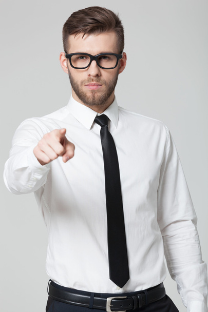 Young handsome businessman pointing at you  isolated on gray bac - 写真・画像