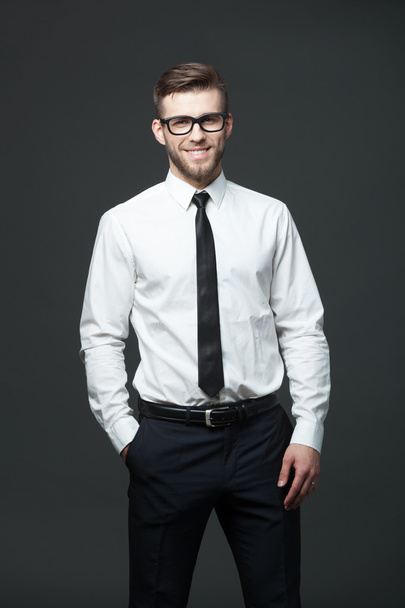 Portrait of handsome young businessman on dark background. - Фото, изображение