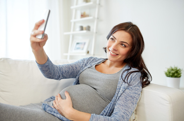 pregnant woman taking smartphone selfie at home - Foto, imagen