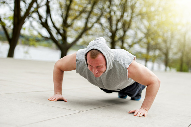 Aktywny człowiek robi push up w parku. - Zdjęcie, obraz