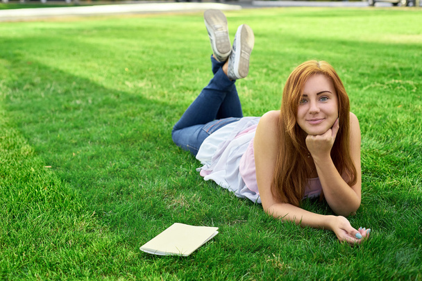 Frau liegt mit Tagebuch auf dem Rasen - Foto, Bild