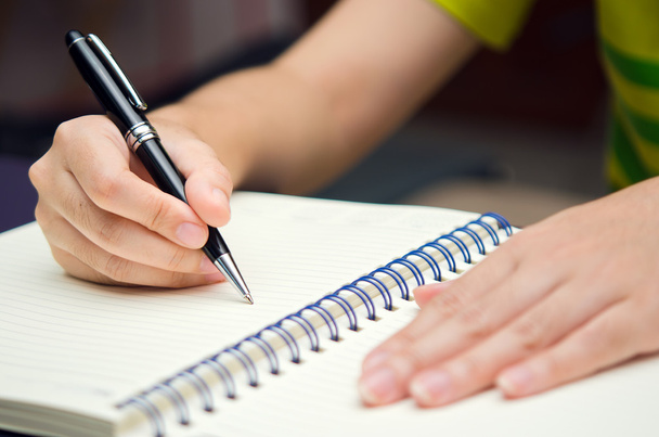 Рука тримає ручку і пише на книзі
 - Фото, зображення