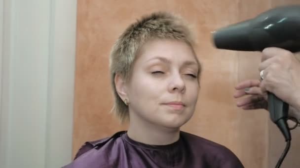 Friseur trocknet und stylt kurze Haare blonden Kopf - Filmmaterial, Video