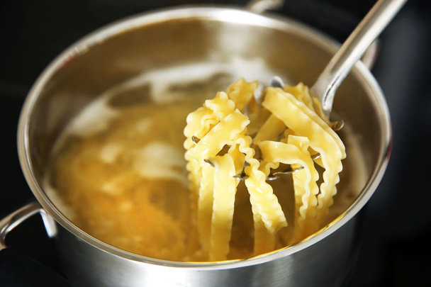 Pasta in spoon over pan on stove - Foto, imagen