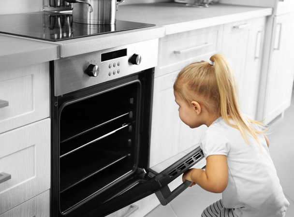 Little girl playing with oven in kitchen - Photo, Image